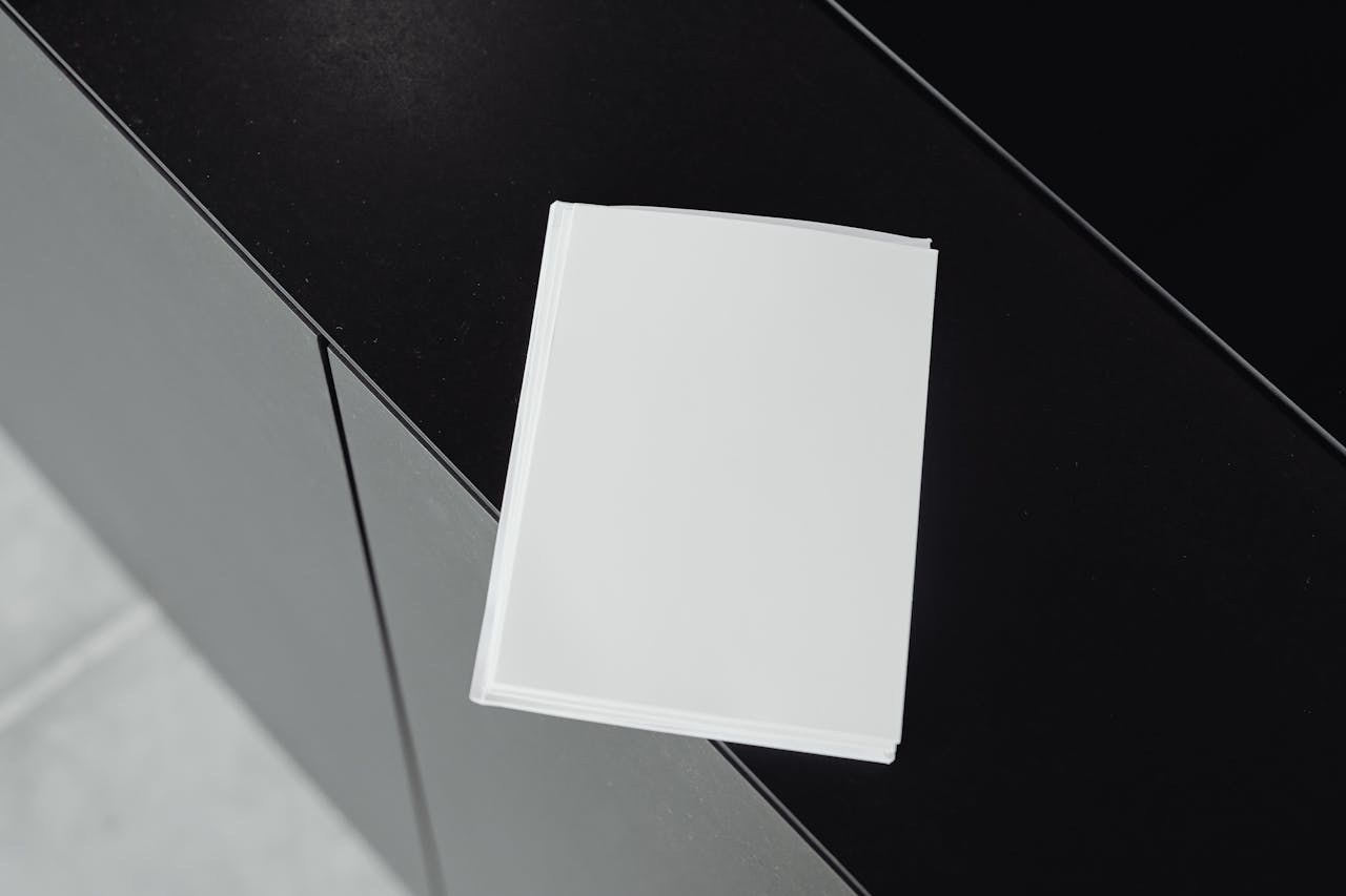 Stack of white papers on black surface offering empty copy space for mockups or designs.