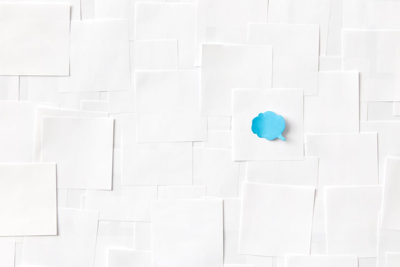 A blue speech bubble on a white paper surface symbolizing communication and ideas.